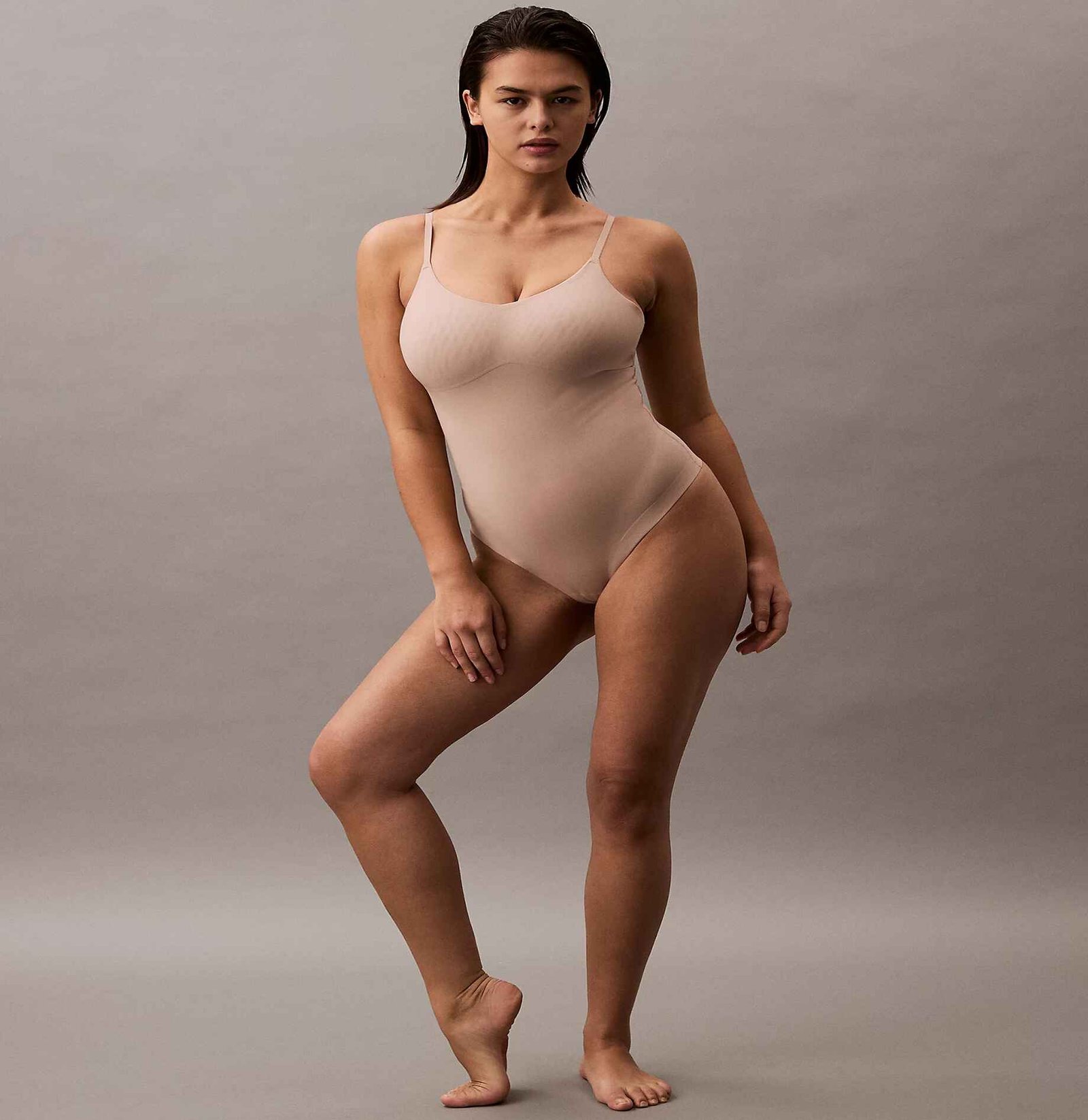 Calvin Klein's Sculpted Shapewear Bodysuit - Stay Put Mesh, provides moderate compression in breathable mesh that stays in place. Features include microfibre and mesh, pull-on thong silhouette, targeted waist and tummy control, sculpting mesh panels at hip and chest, no-show laser cut edges, and snap fastenings at base,