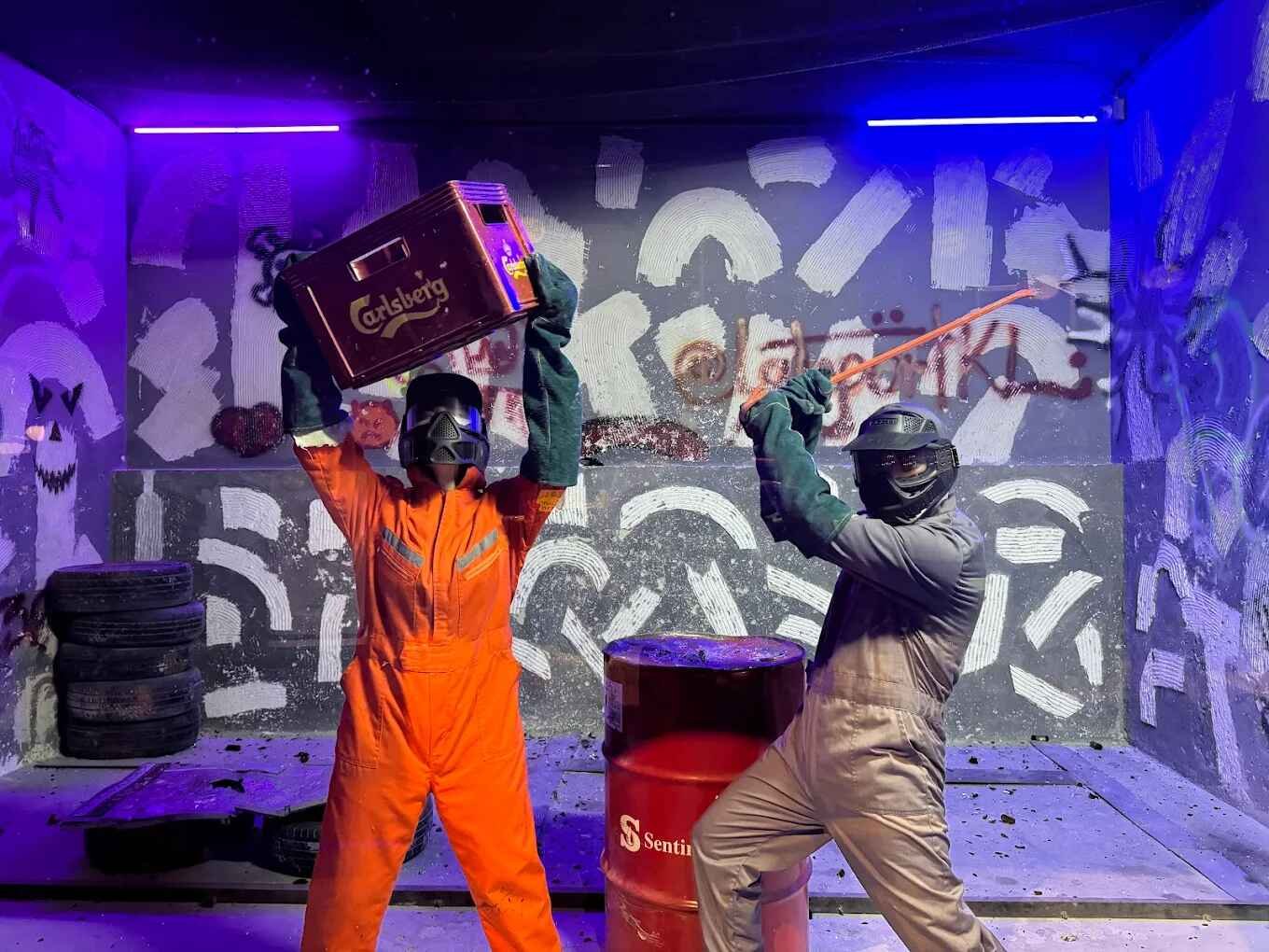Two people unleashing their inner fury in the Rage Room, where you can safely smash objects while rocking out to your favourite tunes at PartyBox360, LaLaport BBCC