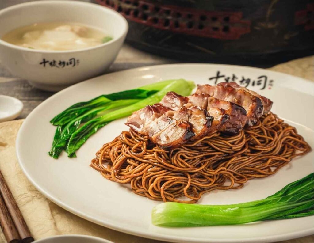 BBQ Pork Wantan Noodle, also known as Char Siu Wantan Mee, is a popular Malaysian dish featuring springy egg noodles, glazed barbeque pork (Char Siu), and savory dumplings filled with a mixture of ground pork, shrimp, and seasonings, served dry with a side of broth bursting with umami.