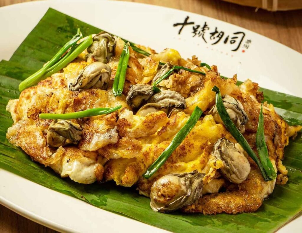 Fried Oyster Omelette from Kong Tai at Lot 10 Hutong KL, a Singaporean-style street food favourite made with fluffy eggs, crispy starch, juicy oysters, and served with spicy chili sauce.