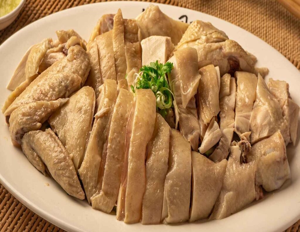 Ipoh Hainanese Chicken Rice, tender poached chicken served with a zesty herb sauce, seasoned rice and seasonal vegetable medley. A signature dish at Chan Thong Kee, Lot 10 Hutong Food Court
