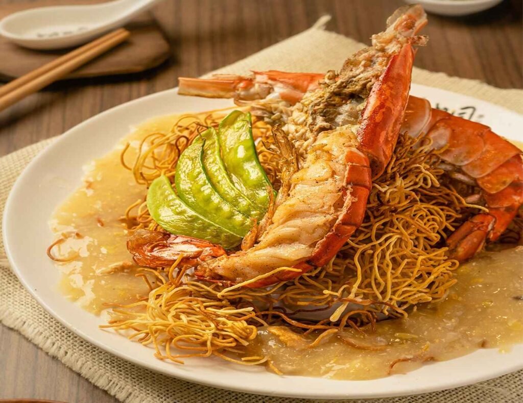 A luxurious plate of King Prawn Noodles from Kedai Makanan Soo Kee Mee at Lot 10 Hutong, featuring golden-fried, springy egg noodles generously topped with succulent freshwater king prawns and smothered in a rich, savory gravy.