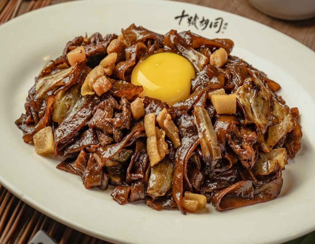 Moonlight Kuey Teow, also known as Moonlight Hor Fun or Moonlight River Noodles (月光河), is a stir-fried rice noodle dish in which a raw egg yolk is cracked on top of the noodles while they are still hot, creating a creamy, rich sauce as the yolk cooks slightly from the heat. A signature dish at Kim Lian Kee in Lot 10 Hutong, it is known for its glistening appearance, resembling the moon shining over a river, hence the name.