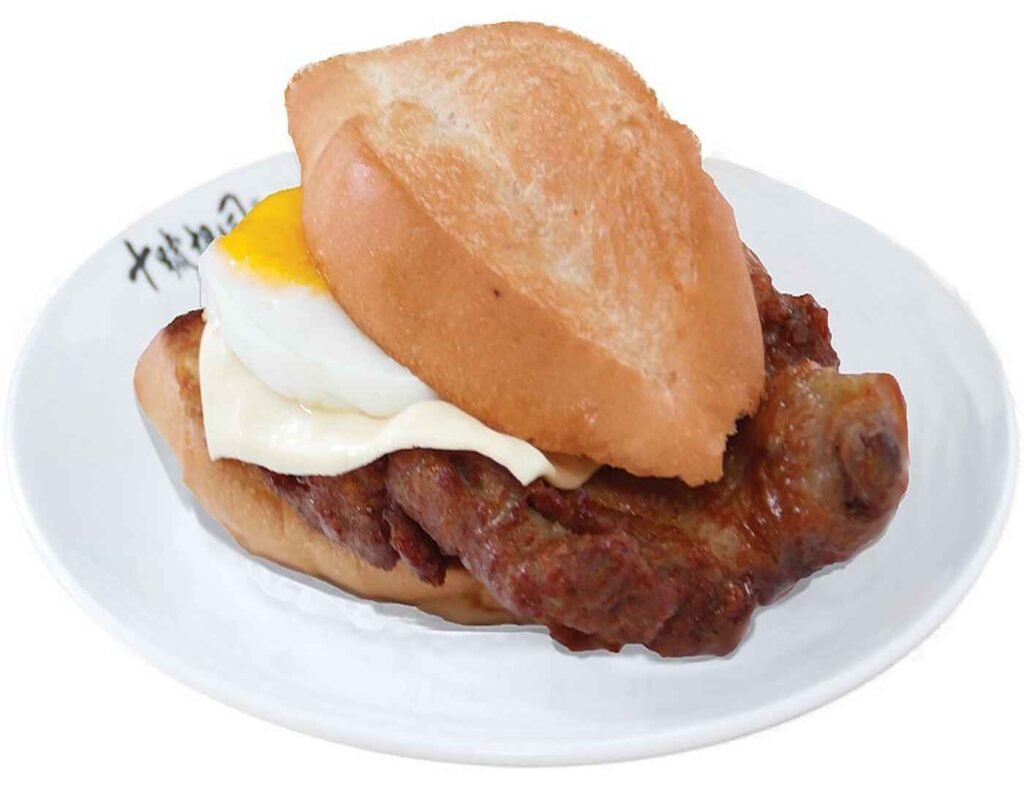 Porco Macau Pork Chop Bun from Lot 10 Hutong, featuring a thick, golden-fried, tender pork chop and a sunny-side-up egg nestled inside a lightly toasted, soft bun, showcasing this iconic Macanese street food dish.