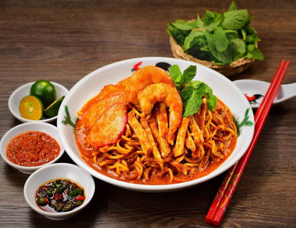 Signature Ipoh Dry Curry Mee from Hei Heng Ipoh at Lot 10 Hutong Food Court, featuring springy yellow noodles coated in a rich, spicy curry gravy, topped with tender char siu (BBQ pork), shredded chicken, fresh prawns, and a sprinkle of fresh mint.