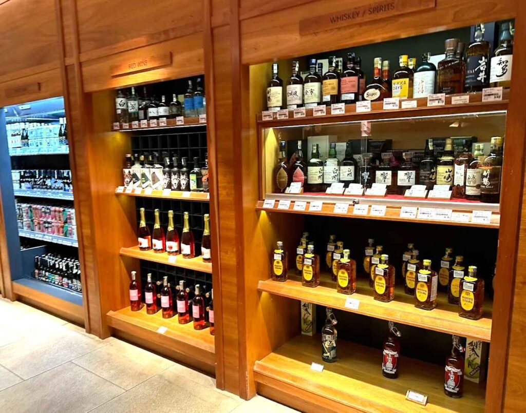 Scotch and Japanese whisky, fine wine, Shochu, and chilled craft beers displayed on warm wood shelves at City Cellar, located at The Market, Lower Ground Floor, Isetan The Japan Store Lot 10, Bukit Bintang, Kuala Lumpur.