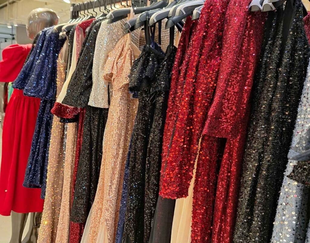 BebeButterfly display rack showcasing shimmering sequined gowns in red, black, gold, silver, and navy blue, with off-shoulder, long-sleeve, and draped designs that highlight the brand’s glamorous cocktail and party-ready style designed for weddings, dinners, and special occasions. Located at The Fashion, First Floor, Isetan The Japan Store Lot 10, Bukit Bintang, Kuala Lumpur.