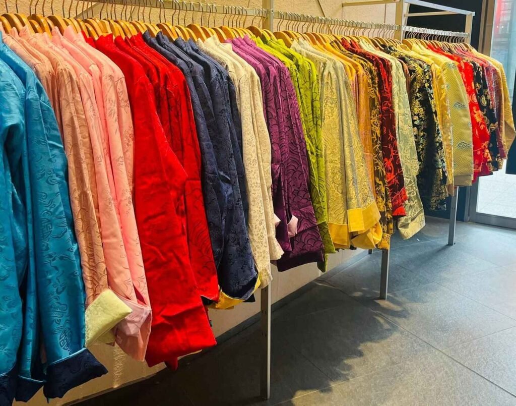 A vibrant collection of colourful samfu tops in red, blue, green, yellow, and black displayed on a rack at Cynthia Tang, a Malaysian designer reinterpreting traditional garments like the samfu, cheongsam, and kebaya with modern fabrics and style, at The Design, Isetan The Japan Store Lot 10, Bukit Bintang, Kuala Lumpur.