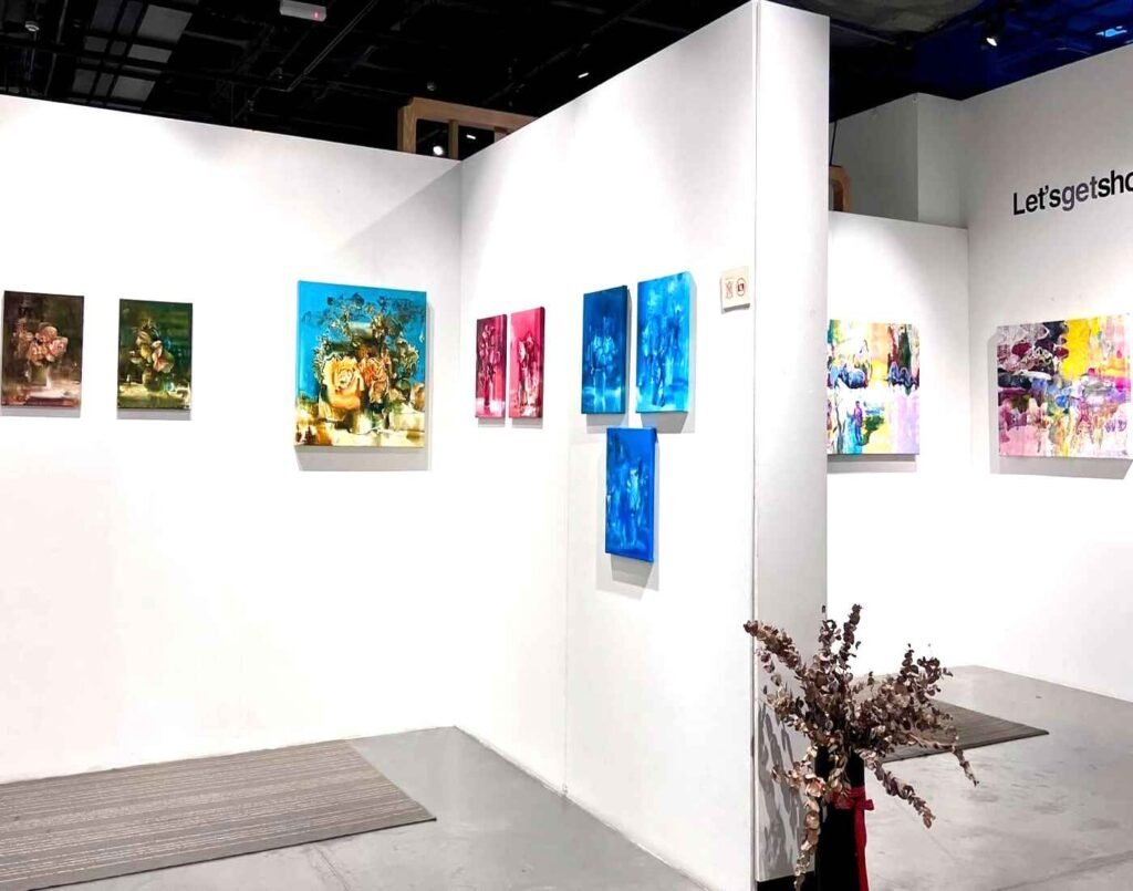 Contemporary paintings by Malaysian artists — floral still lifes, blue-toned portraits and abstract colour fields hung on white partition walls in a rotating exhibition space at Gallery 10, known for showcasing fine art from both established and emerging Malaysian artists, located at The Wellness, Second Floor, Isetan The Japan Store Lot 10, Bukit Bintang, Kuala Lumpur.