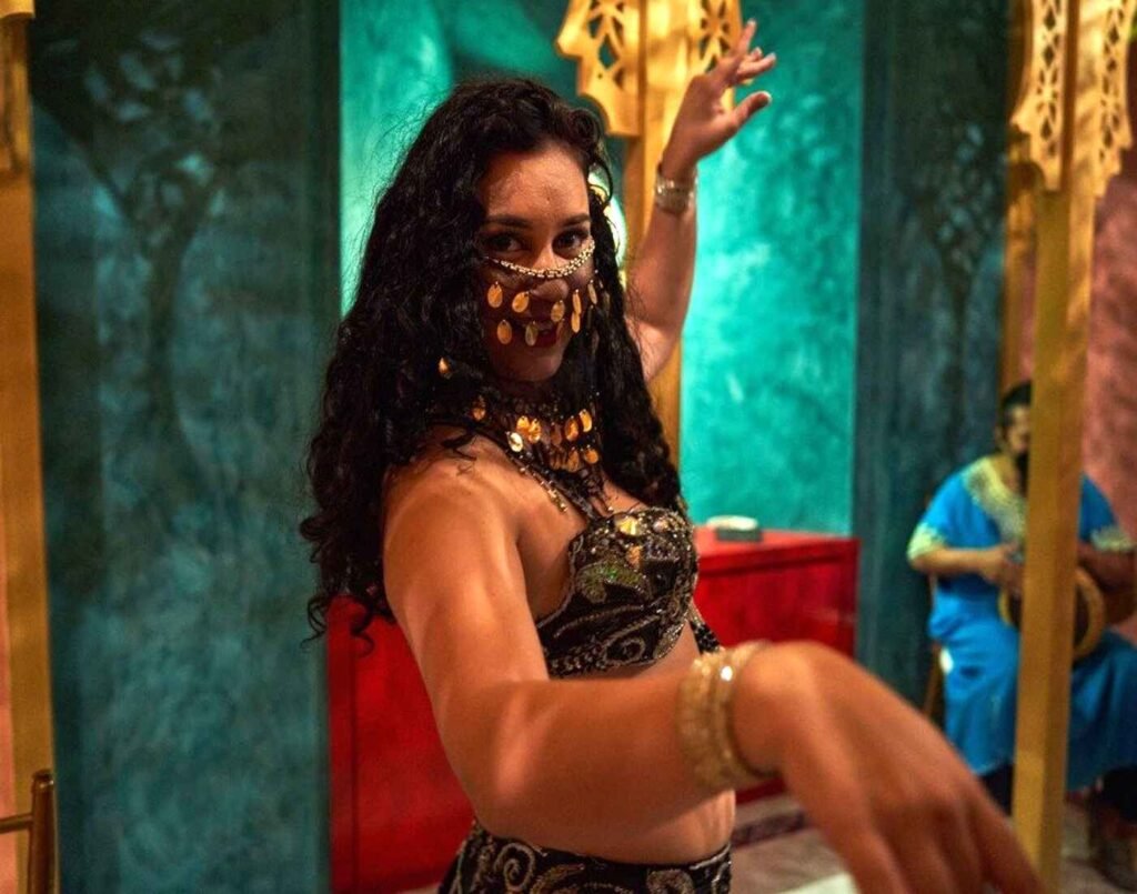 An Arabian belly dancer performing the welcome dance at Hammam Spa, wearing a face veil and traditional bedlah with vibrant beadwork and sequin decoration, consisting of a fitted bra and a long skirt with a slit, exposing her midriff and thigh, entertaining guests as part of the Moroccan-inspired cultural experience at Hammam Spa, The Wellness, Second Floor, Isetan The Japan Store Lot 10, Bukit Bintang, Kuala Lumpur.