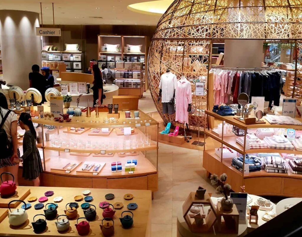 Display of colourful cast-iron teapots with matching trivets, glassware, small bowls, folded towels, bath linens, bedding sets, pyjamas on mannequins and racks, fine mirrors, and assorted lifestyle goods inside The Design, Ground Floor, Isetan The Japan Store Lot 10, Bukit Bintang, Kuala Lumpur.