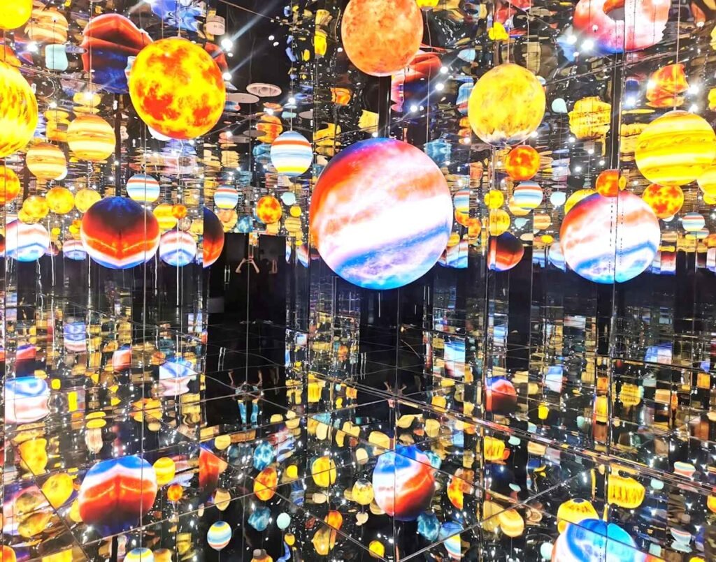 The Wandering Planets exhibit features hundreds of glowing LED spheres suspended in a mirrored infinity room. The spheres are illuminated from within, casting a soft, warm glow in a variety of vibrant colors, including deep reds, yellows, and blues, reminiscent of real stars and planets. A favourite Instaworthy zone at Space & Time Cube, The Amusement, Third Floor, Isetan The Japan Store Lot 10, Bukit Bintang, Kuala Lumpur.