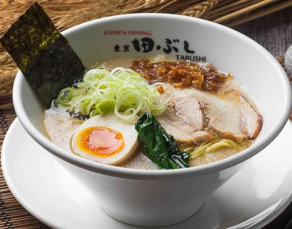 Tonkotsu Shoyu Ramen features springy noodles in a bowl of savoury, creamy and thick tonkotsu shoyu broth, topped with ajitama, roasted pork belly, bamboo shoot, greens, garlic sauce, egg, nori seaweed and chopped leeks. A highly rated dish at Tabushi Ramen Dining, famous for its rich tonkotsu broth layered with umami-packed bonito oil and tender in-house noodles, located at The Market, Lower Ground Floor, Isetan The Japan Store Lot 10, Bukit Bintang, Kuala Lumpur.