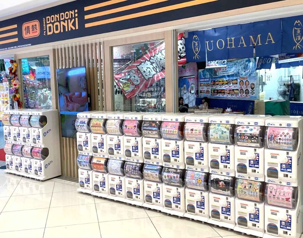 Japanese gashapon capsule machines at the entrance of the second floor at Don Don Donki Lot 10 featuring a wide variety of collectible capsule toys and anime merchandise.
