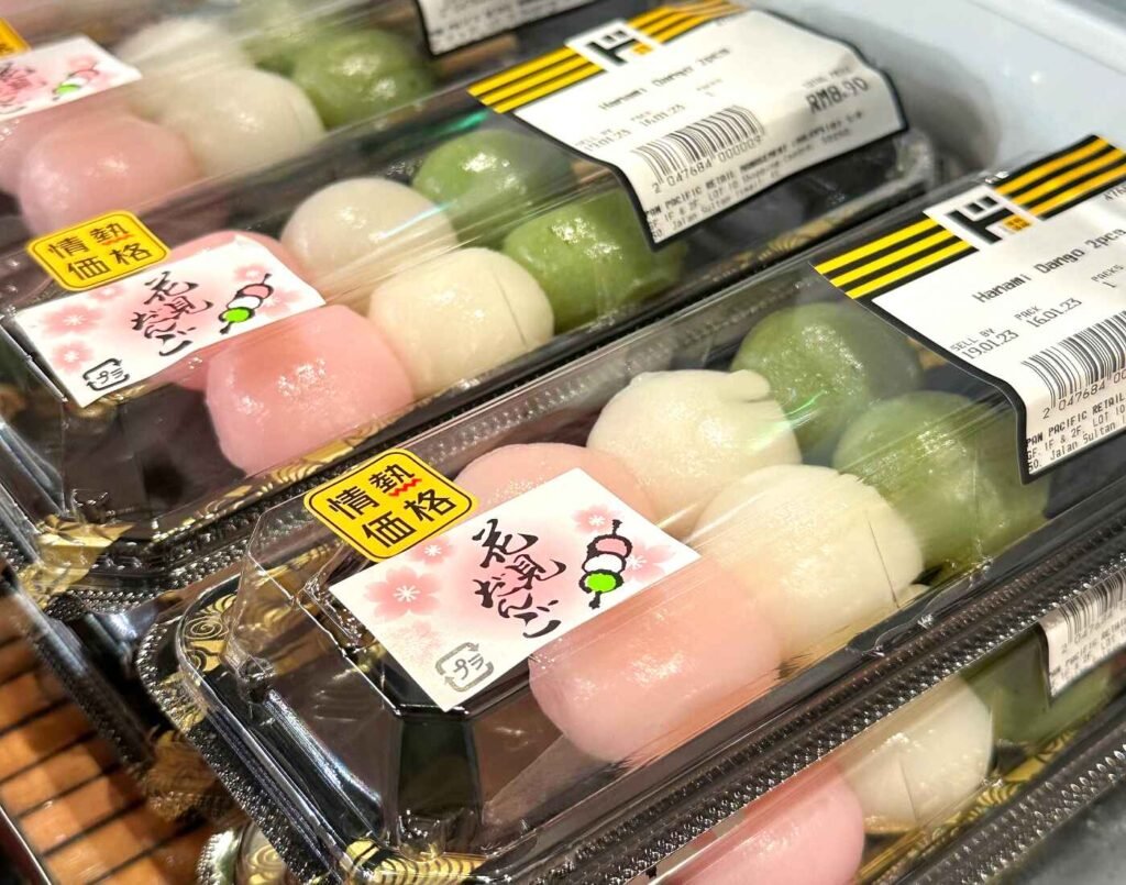 Hanami Dango (also known as Sanshoku Dango) skewers in pastel pink (sakura), white (plain), and green (matcha) — a traditional Japanese sweet made with a blend of Shiratamako and Joshinko rice flours, enjoyed during cherry blossom season in spring. Neatly packed and displayed in the chiller at Jonetz By Don Don Donki Lot 10, a Japanese supermarket in Bukit Bintang, Kuala Lumpur.