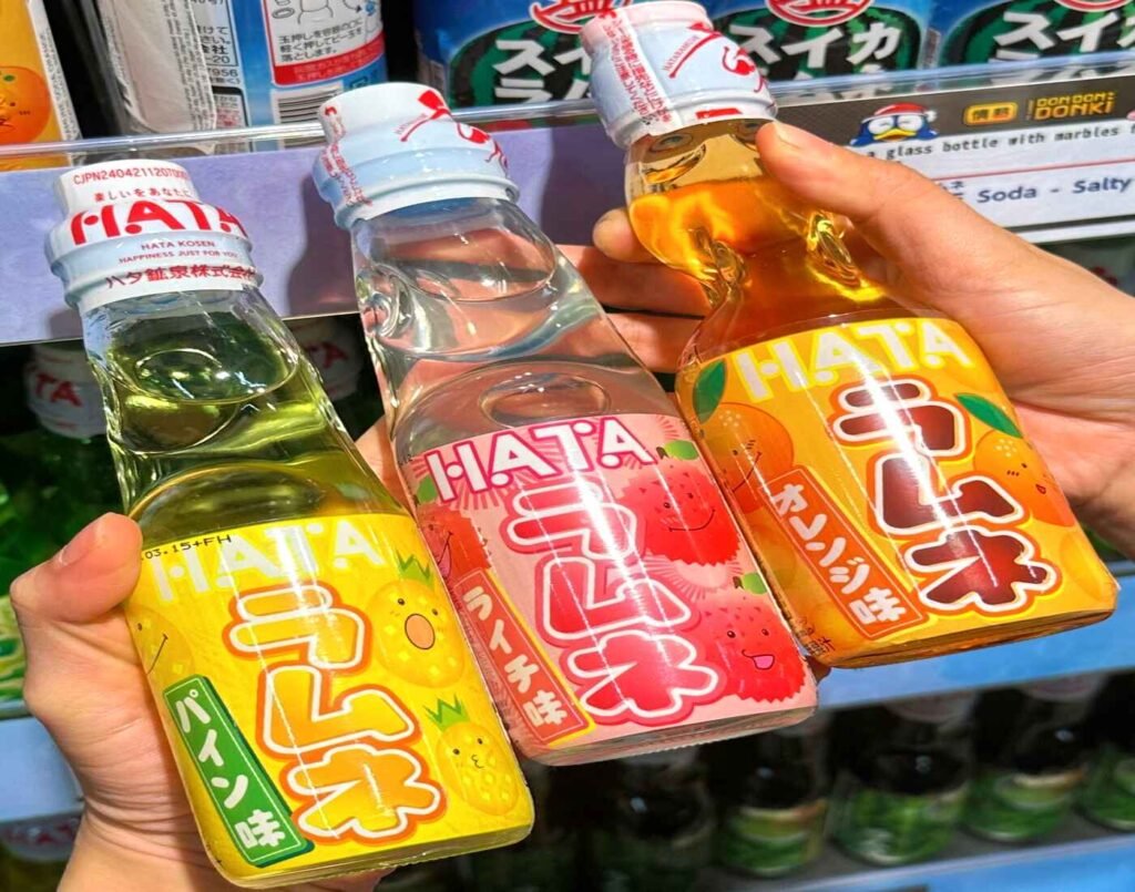Glass bottles of Hata Ramune Japanese soda in Pineapple (yellow label), Lychee (pink label), and Orange (orange label) flavours at Jonetz By Don Don Donki Lot 10.