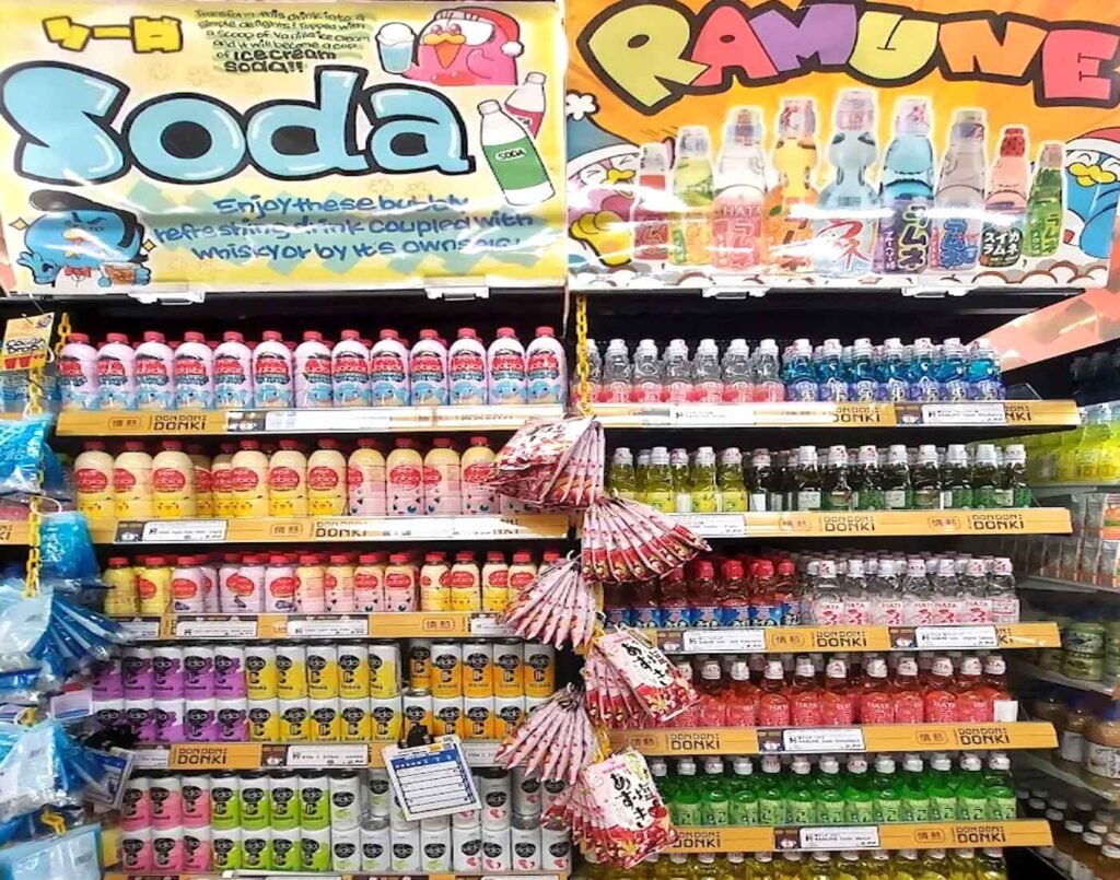 A colourful display of Japanese ramune, flavoured sodas, and sparkling drinks in glass bottles and cans, featuring classic marble-sealed Hata Ramune alongside modern fizzy options such as Vida sparkling drinks, available at Jonetz By Don Don Donki Lot 10 in Bukit Bintang, Kuala Lumpur.