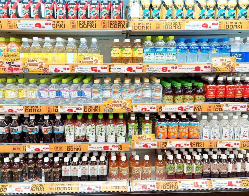 A chilled display of popular Japanese ready-to-drink beverages including Pocari Sweat, Aquarius, Green Dakara, Kirin Lemon Soda, Suntory Craft Boss Tea, Lipton Lemon Tea, Japanese barley tea (Mugicha), green tea, fruit-flavoured sparkling drinks, bottled mineral water, and canned energy drinks, arranged with promotional pricing at Jonetz By Don Don Donki Lot 10 in Bukit Bintang, Kuala Lumpur.