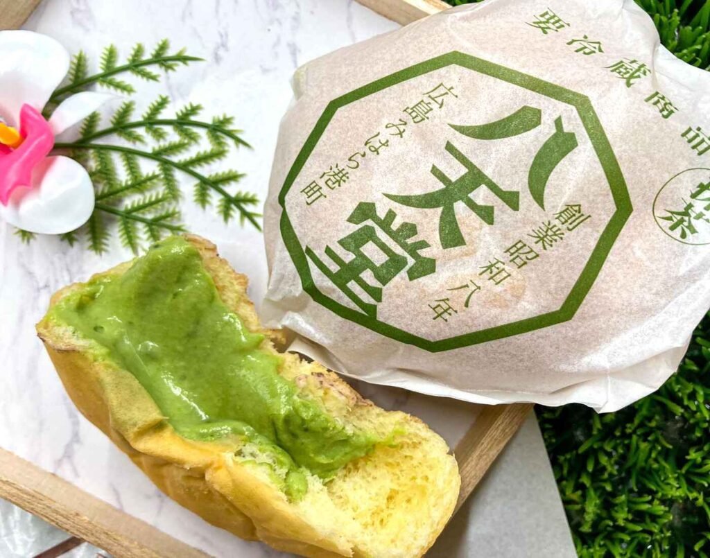 Hattendo Matcha Cream Bun cut in half, showing the rich green tea filling inside. A popular Halal-certified Japanese snack available at Jonetz By Don Don Donki Lot 10, a Japanese supermarket in Bukit Bintang, Kuala Lumpur.