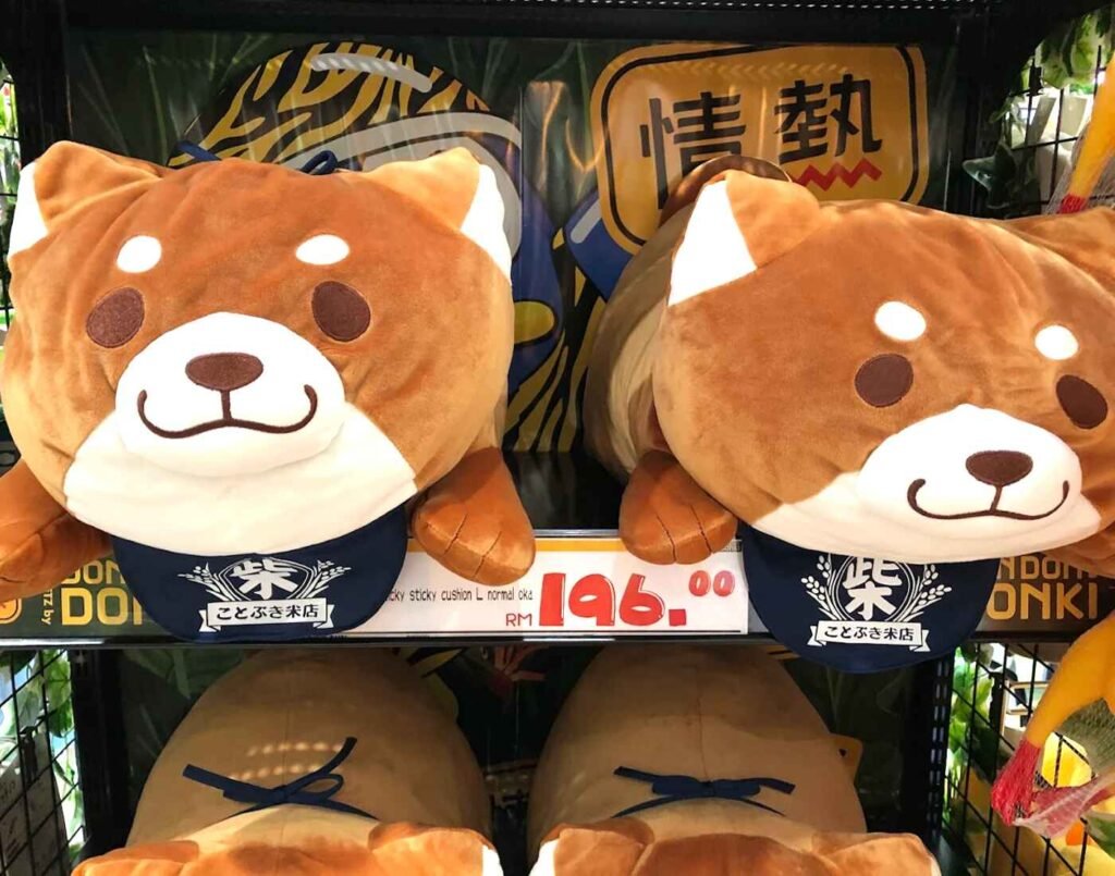 Large Shiba Inu plush cushions displayed on shelves in the kawaii merchandise section at Don Don Donki Lot 10, Bukit Bintang, Kuala Lumpur.