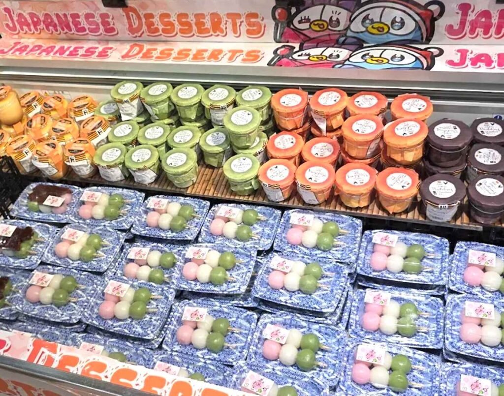 Chilled Japanese desserts featuring trays of pink, white, and green Hanami Dango, Jelly Cups, as well as small tubs of Matcha, Chocolate and custard flavoured puddings at Jonetz By Don Don Donki Lot 10, a Japanese supermarket in Bukit Bintang, Kuala Lumpur.