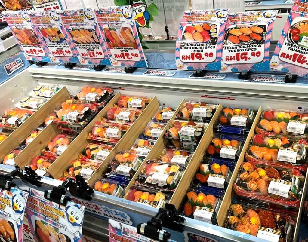 Assorted sushi trays including nigiri and maki rolls displayed in the chilled seafood section at Jonetz By Don Don Donki Lot 10, a Japanese supermarket in Bukit Bintang, Kuala Lumpur.