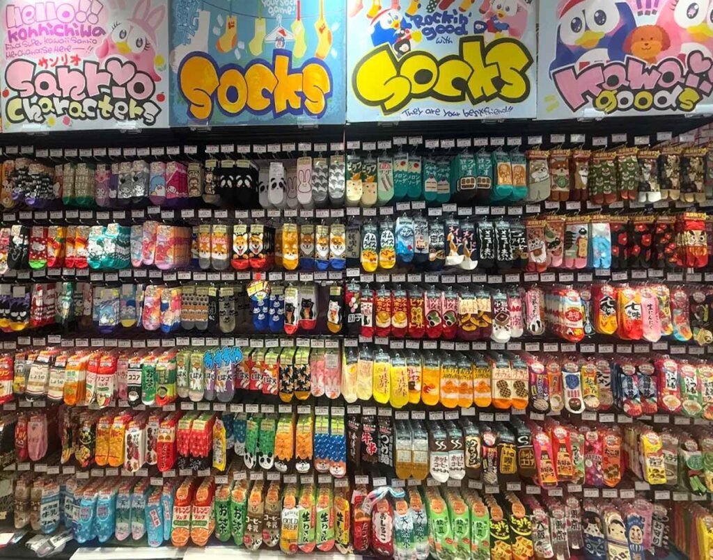 Full wall of Japanese character socks featuring Sanrio designs, anime-inspired graphics and J-pop culture motifs at the Kawaii Corner inside Don Don Donki Lot 10.