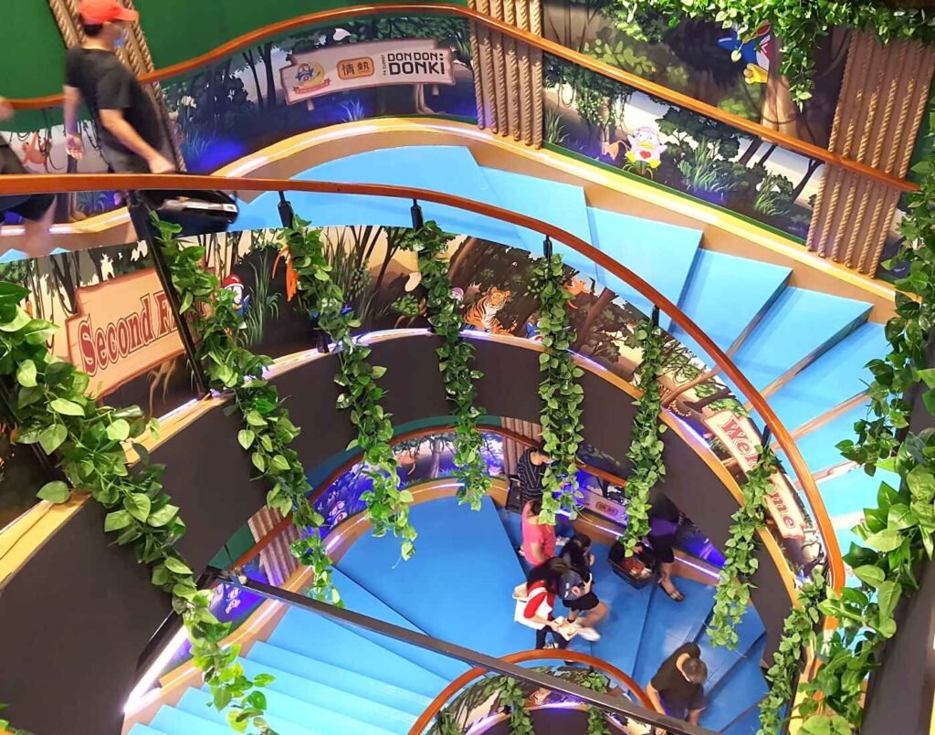 Spiral staircase connecting the ground, first and second floors at Don Don Donki Lot 10 in Bukit Bintang, Kuala Lumpur, showcasing the store’s unique multi-level layout and jungle-themed interior design.