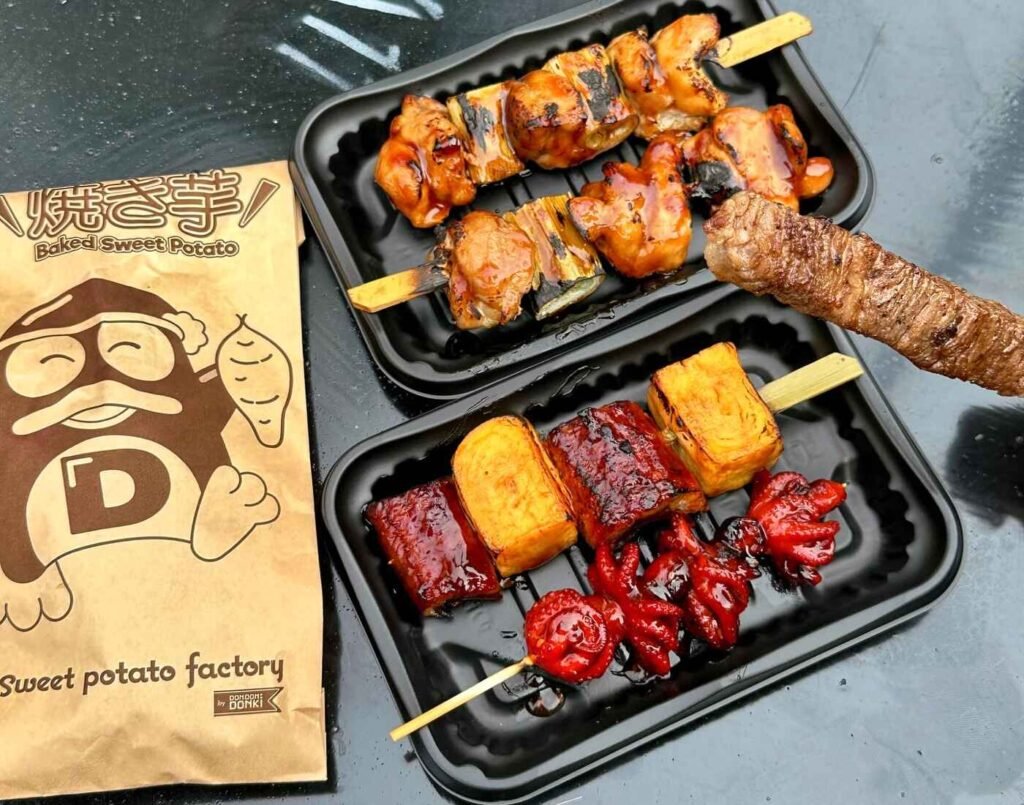 Assorted Japanese street food from the Sweet Potato Factory including a baked potato, wagyu skewers, chicken yakitori, takoyaki, and tamago, freshly grilled and served at Jonetz By Don Don Donki Lot 10, a Japanese supermarket in Bukit Bintang, Kuala Lumpur.