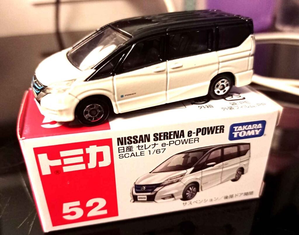 A 1/67 scale Nissan Serena e-POWER Tomica 52 die-cast vehicle released in April 2018 by Takara Tomy featuring a white body, black roof, and opening rear door functionality.