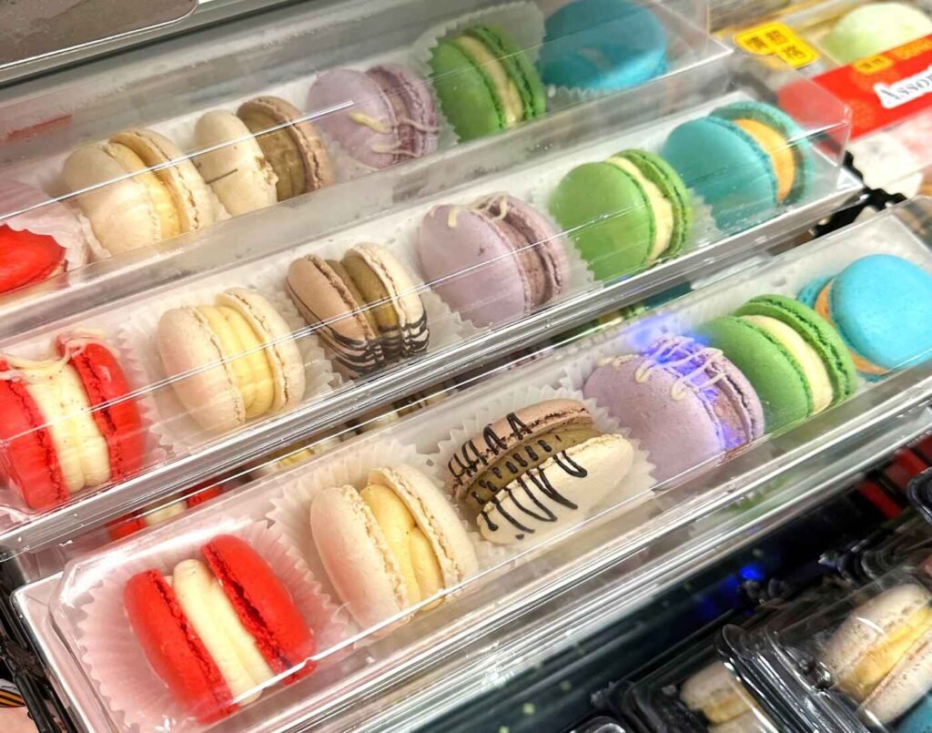 Assorted colourful macarons in clear plastic packs, each containing 6 pieces of macarons featuring flavours like pistachio, lavender, vanilla, chocolate and fruits, on display at the chilled Japanese desserts section at Jonetz By Don Don Donki Lot 10, a Japanese supermarket in Bukit Bintang, Kuala Lumpur.