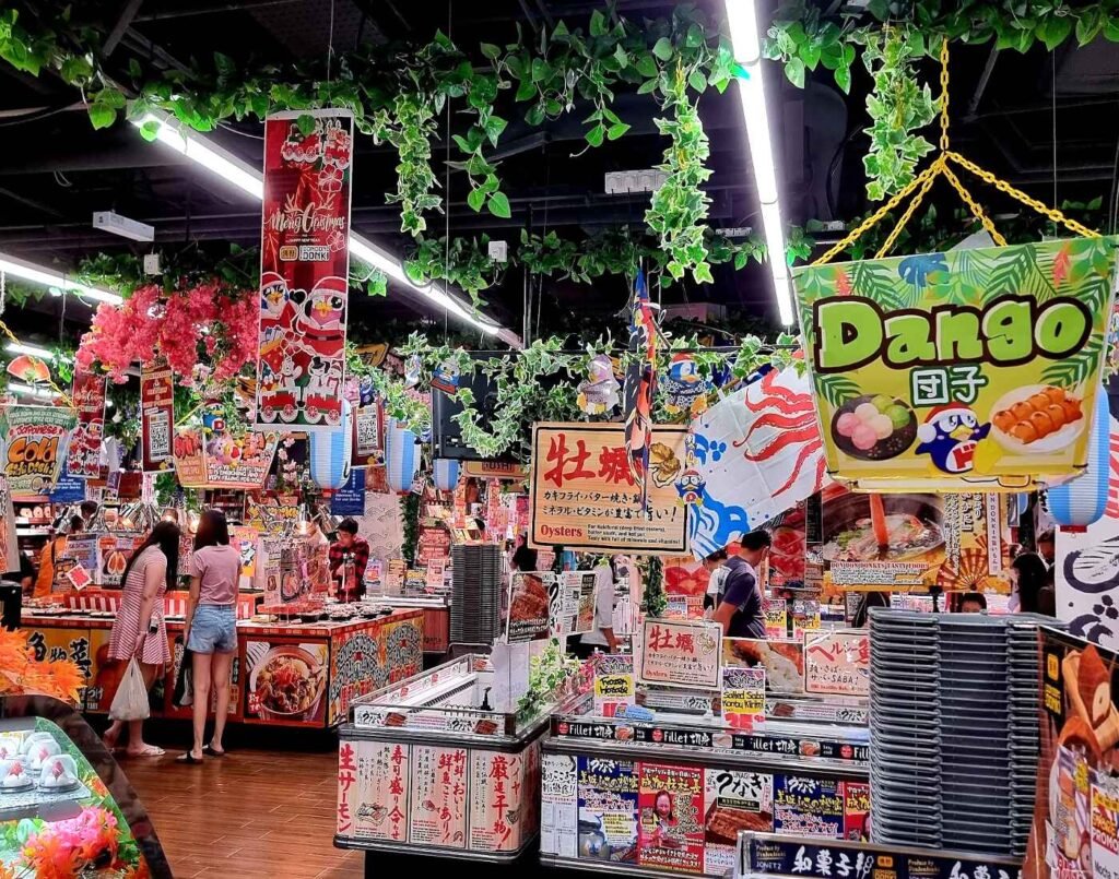 The vibrant 1st floor of JONETZ by Don Don Donki Lot 10, showing the fresh produce area, chilled desserts, and the ready-to-eat bento and fresh seafood sections.