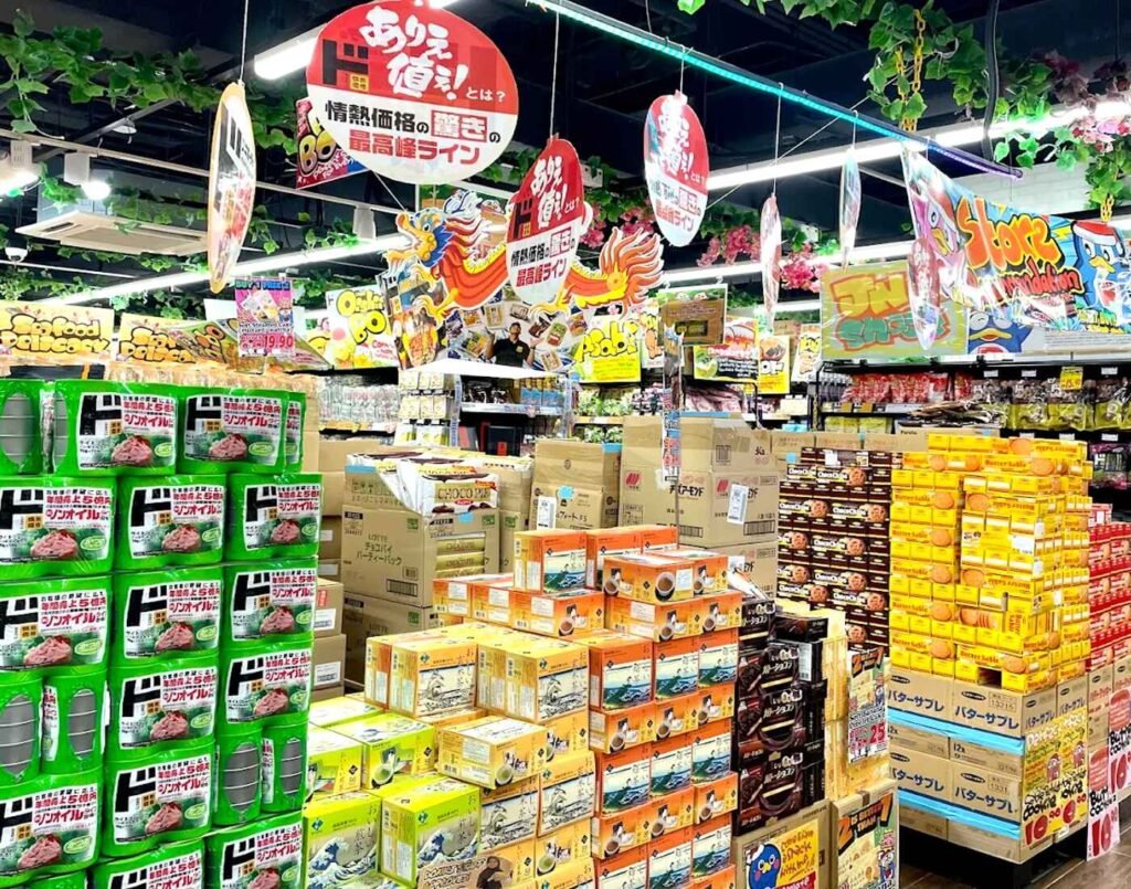 An aisle at JONETZ by Don Don Donki Lot 10 in Bukit Bintang filled with Jonetsu Kakaku (Passionate Price) house brand snacks, featuring bulk displays of Japanese biscuits, tea, and seasonal discount signage for bargain hunters.